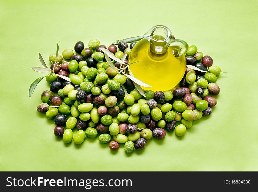 Olive oil and olives on green background