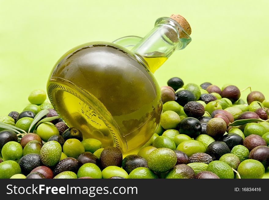 Olive oil and olives on green background