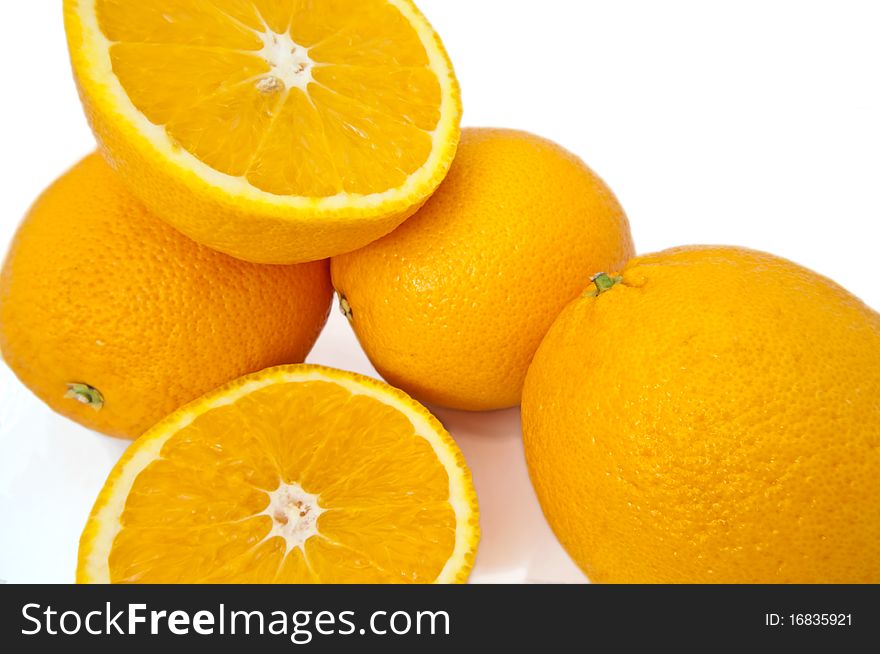 Close up capturing several fresh whole and cut oranges over white. Close up capturing several fresh whole and cut oranges over white.