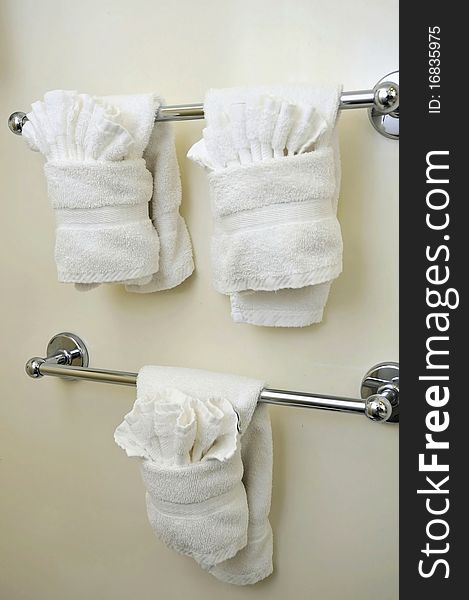 Clean and folded white towels hanging in the bathroom.