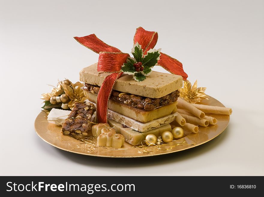 Typical Spanish Christmas nougat in a golden plate. White background.