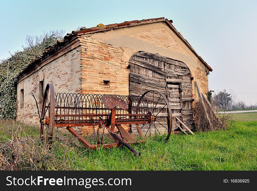 View over the countryside with a ruin of a hut and an old agriculture machinery. View over the countryside with a ruin of a hut and an old agriculture machinery