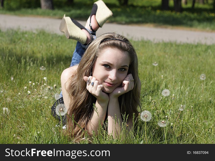 Young women lying on green grass in dandelions