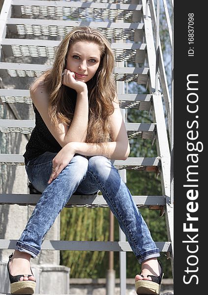 Pretty Lovely brunette girl sitting on the stairs