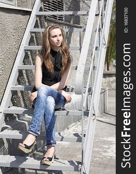 Lovely brunette girl sitting on the stairs. Lovely brunette girl sitting on the stairs