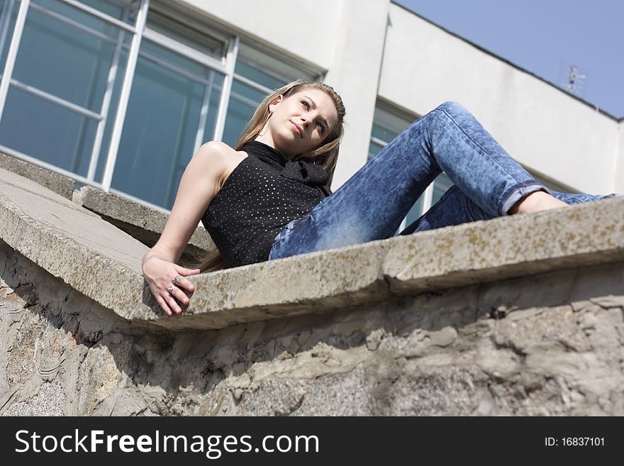 Pretty brunette teenage girl sitting on the wall outdoor
