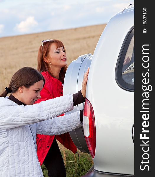 The car is pushed by women in a field