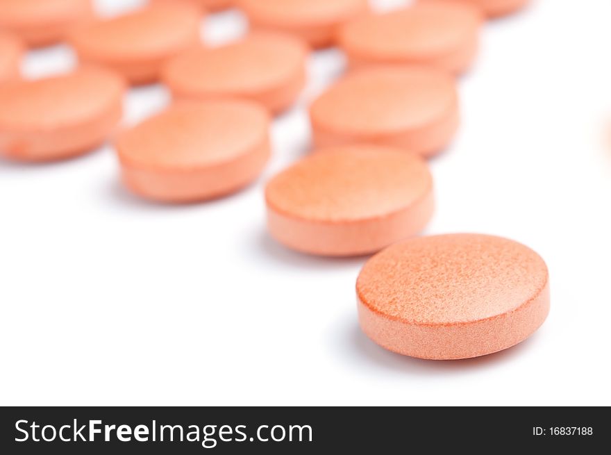 Close-up of orange pills, isolated on white, selective focus. Close-up of orange pills, isolated on white, selective focus.