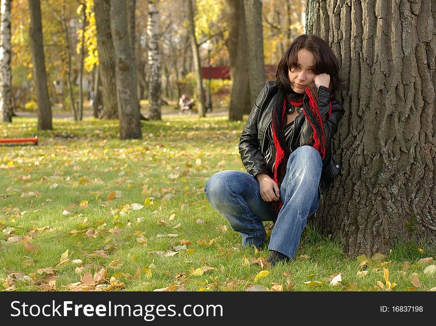 Female sitting on the green grass with yellow leaves. Female sitting on the green grass with yellow leaves