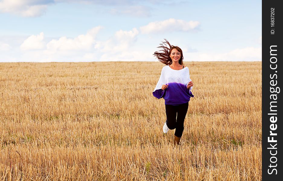 A beautiful woman is running through the field. A beautiful woman is running through the field