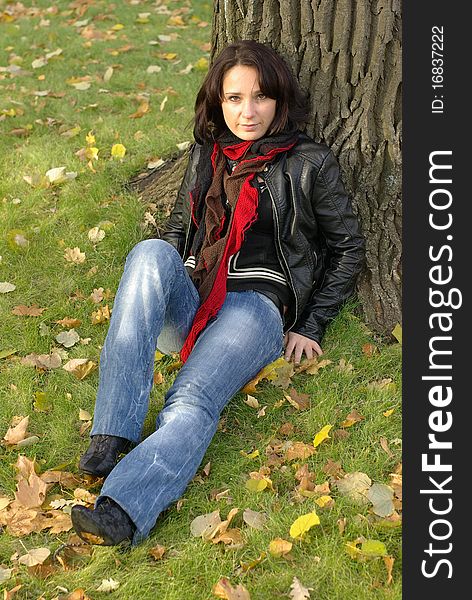 Girl sitting under the tree in an autumn park. Girl sitting under the tree in an autumn park