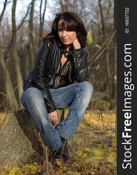 Girl sitting on a stump in an autumn park