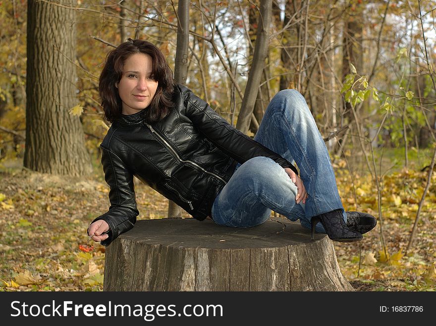 Girl sitting cross-legged on a stump in the autumn forest. Girl sitting cross-legged on a stump in the autumn forest