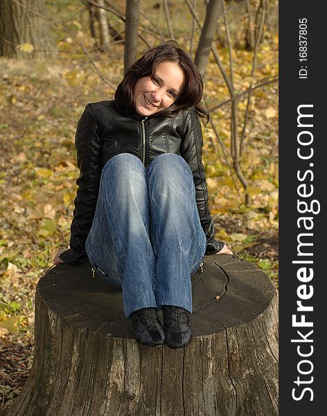 Woman sitting on a stump in an autumn park. Woman sitting on a stump in an autumn park