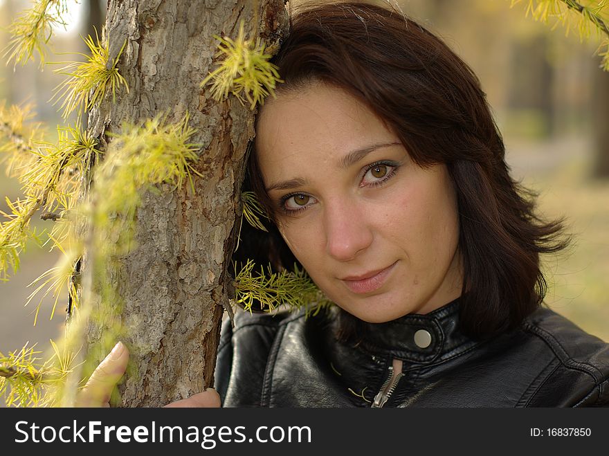 Girl in a coniferous forest leaning against a fir-tree