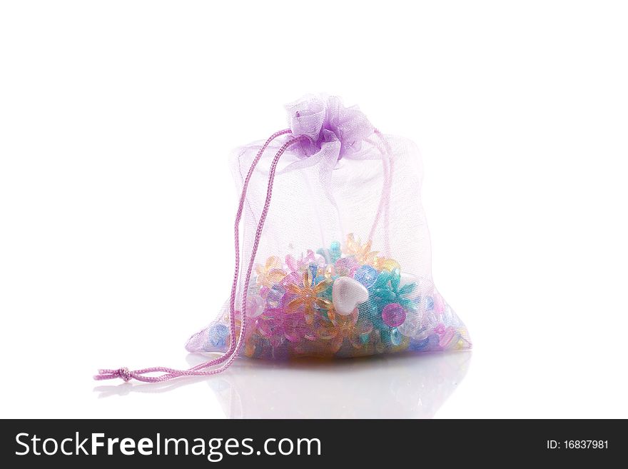 Colored beads in a lavender bag isolated on white