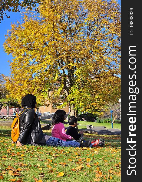 A happy and active Malaysian family sitting together bonding on the lawn , watching autumn leaves turn colour , and having a picnic. A happy and active Malaysian family sitting together bonding on the lawn , watching autumn leaves turn colour , and having a picnic.