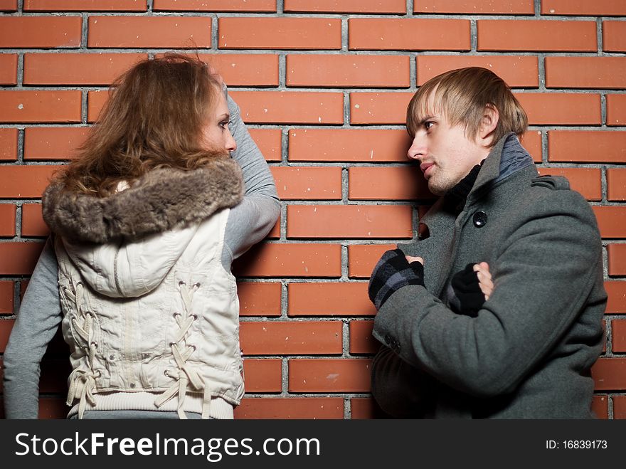 Young couple at the brick wall at fall season