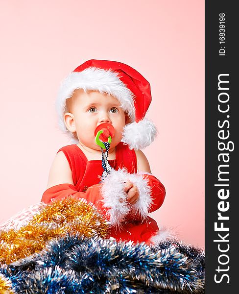 Baby in Santa Claus hat on pink background