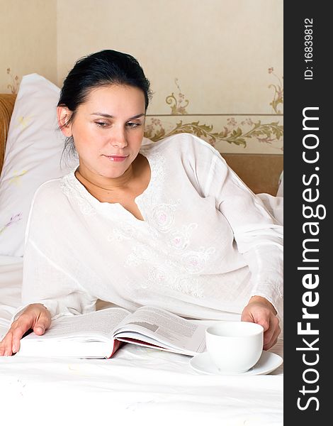 Portrait of young woman with white cup and book on bed at bedroom. Portrait of young woman with white cup and book on bed at bedroom