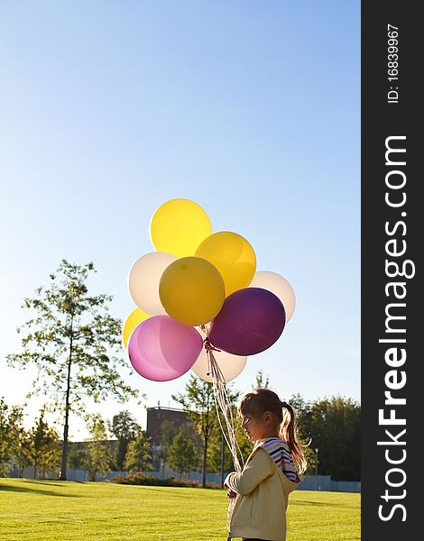 A child with multi-colored balloons