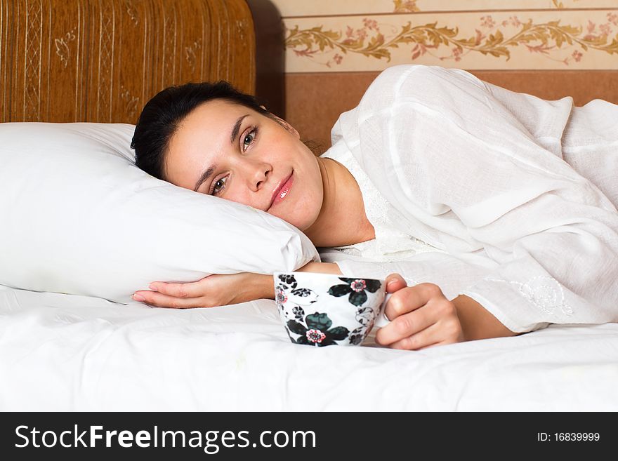 Woman lying in bed and tasting coffee