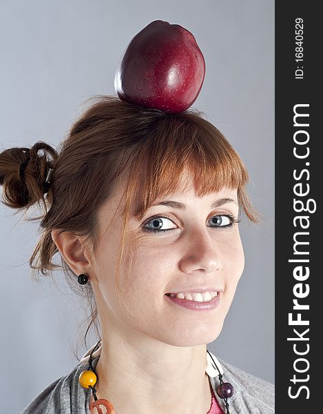 Young girl with pigtails, and colorful necklace and an apple on her head. Young girl with pigtails, and colorful necklace and an apple on her head