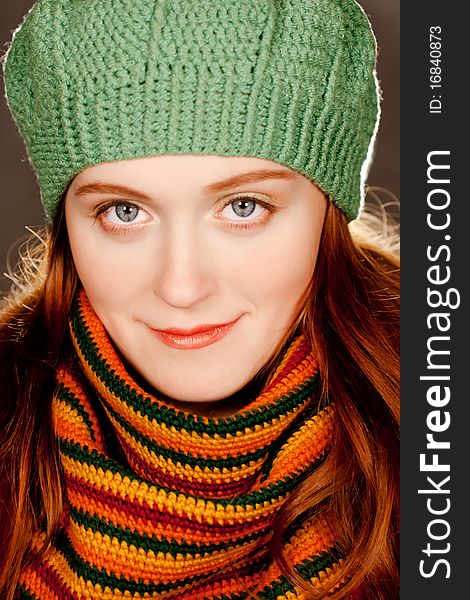 Young beautiful redhead girl in a green beret and a colorful autumn knitted scarf. Young beautiful redhead girl in a green beret and a colorful autumn knitted scarf
