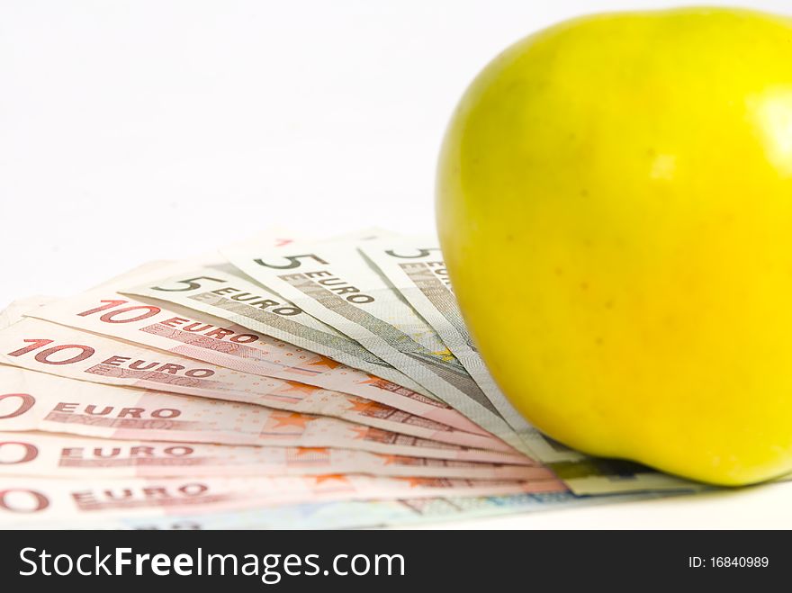 Green apple lying on the banknotes of different denomination, lying like a fan. on a white background, close-up. Green apple lying on the banknotes of different denomination, lying like a fan. on a white background, close-up