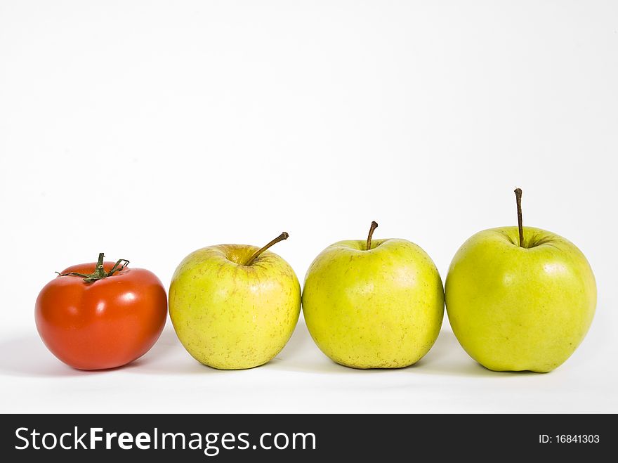 Red ripe tomato, and green apples lying in a row on a white background. Red ripe tomato, and green apples lying in a row on a white background