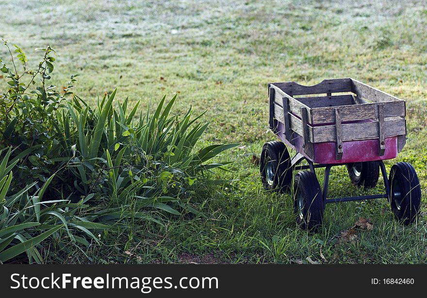 A child's wagon in the yard at dawn with dew on the grass. A child's wagon in the yard at dawn with dew on the grass.