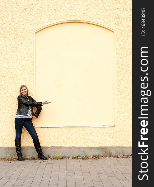 Girl standing in front of wall pointing. Girl standing in front of wall pointing.
