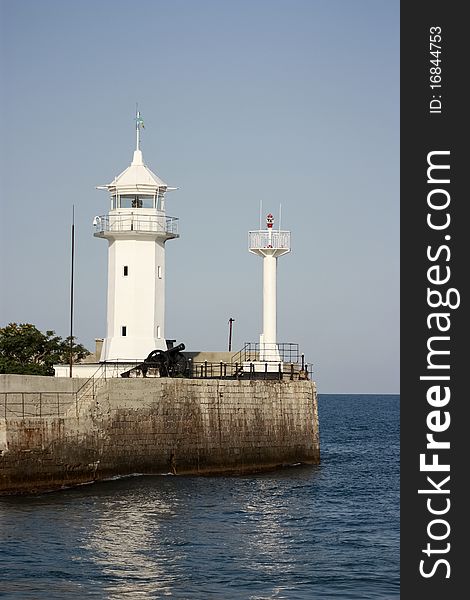 Coastal beacon with an artillery cannon on the stone basis at the sea