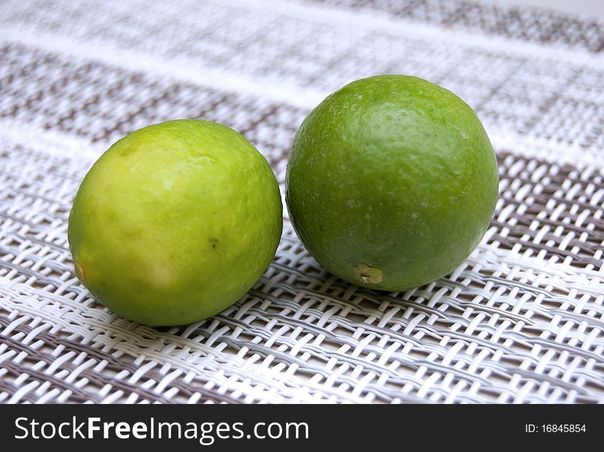 Two small limes, one yellow and one green. Two small limes, one yellow and one green