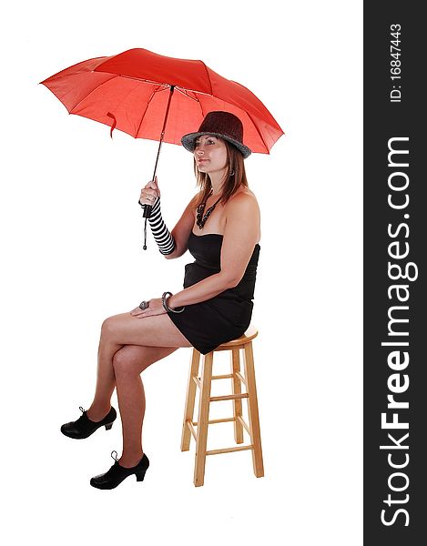 An middle aged woman in an short black dress and a gray hat sitting in the studio with a red umbrella in her hand. An middle aged woman in an short black dress and a gray hat sitting in the studio with a red umbrella in her hand.