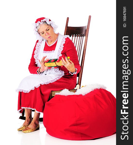 Mrs. Claus inspecting one of Santa's toys before loading it into his sack.  Isolated on white. Mrs. Claus inspecting one of Santa's toys before loading it into his sack.  Isolated on white.