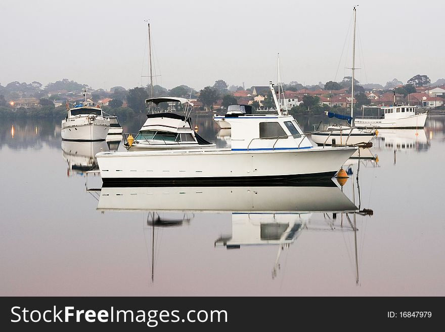 Boats moored in early morning, on calm, glassy water. Boats moored in early morning, on calm, glassy water.