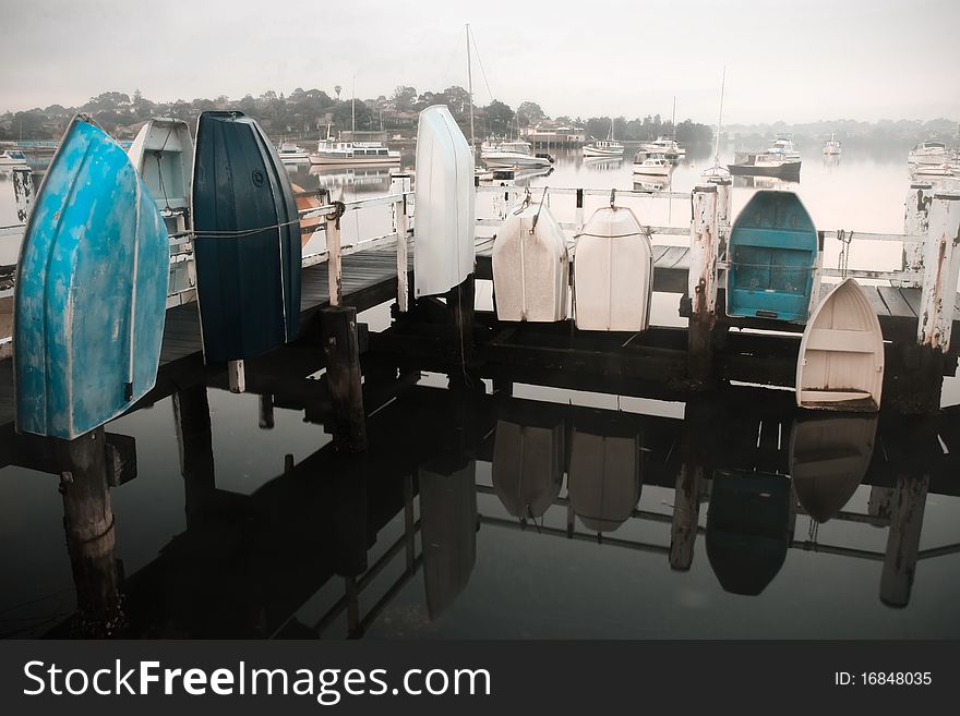 Row boats tied to jetty handrails in ealy morning. Row boats tied to jetty handrails in ealy morning.