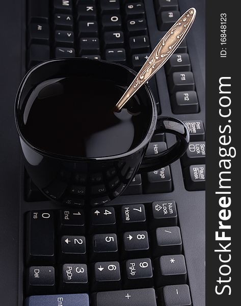 Black cup of coffee on a computer keyboard, contept of business still-life
