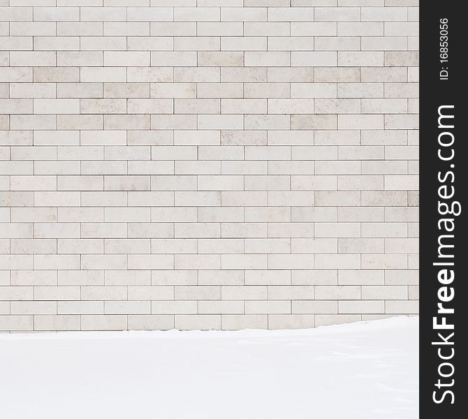 A white brick wall and a ground covered with snow. May use as a background.