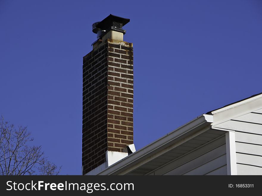 A red brick chimney against a blue sky.