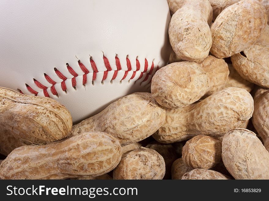 Nuts Peanuts on a table together with a baseball ball.