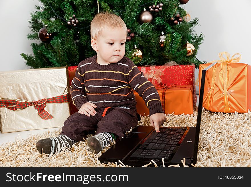 Baby boy playing with a laptop at christmas