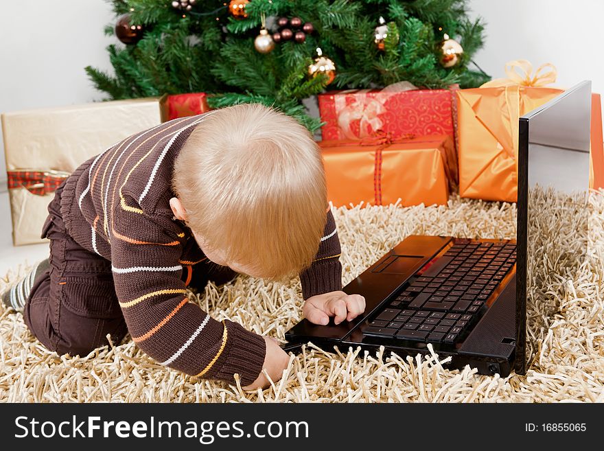 Baby boy playing with a laptop at christmas