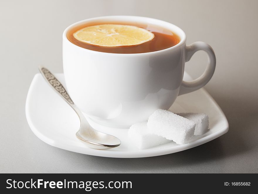 Cup of Tea with lemon slice and sugar on gray table