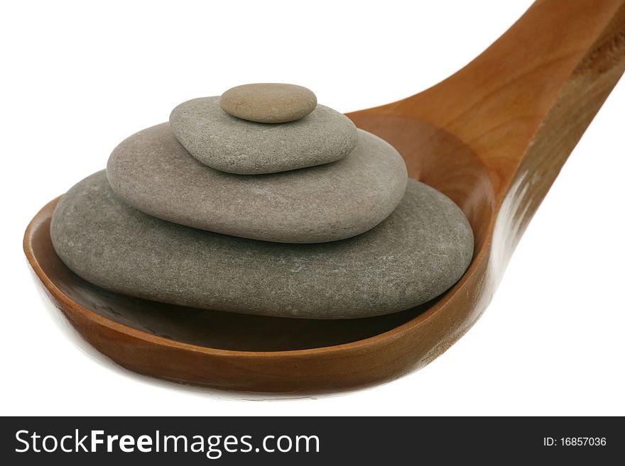 Pile of stones in a wooden spoon over white