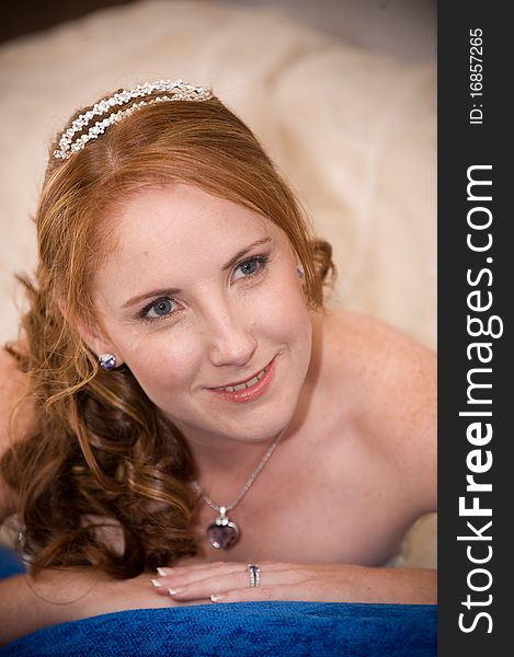 Red head beautiful bride laying down on her elbows with cleavage visible and leaning on her hands whilst smiling. Red head beautiful bride laying down on her elbows with cleavage visible and leaning on her hands whilst smiling