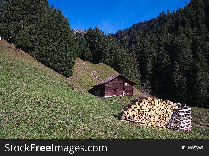 Swiss mountain scene: wooden hut and woodpile in forest mountains. Swiss mountain scene: wooden hut and woodpile in forest mountains