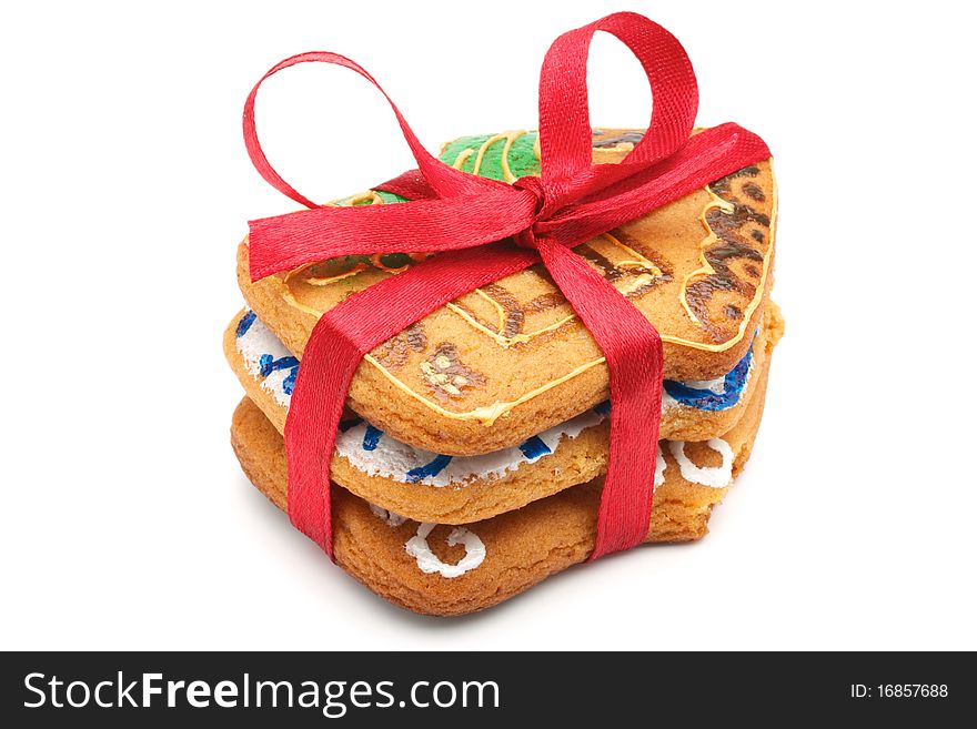 A stack of Christmas cookies in the amount of three pieces. Cookies in the shape of little houses. Pile tied a red ribbon. Painted and baked cookies manually. Isolated on white background. A stack of Christmas cookies in the amount of three pieces. Cookies in the shape of little houses. Pile tied a red ribbon. Painted and baked cookies manually. Isolated on white background.