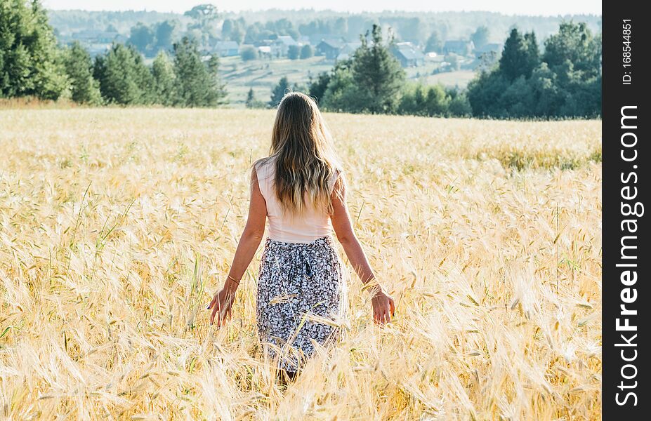 Portrait of a beautiful young woman in a dress on the wheat field
